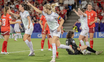 Ada Hegerberg points in the distance as she runs to celebrate her goal, Switzerland players and the goalkeeper look down, distraught in the background.