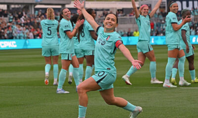 Kansas City Current midfielder Lo'eau LaBonta strikes a pose while celebrating a goal. She is lunging forward on one knee with both arms extended to her sides.